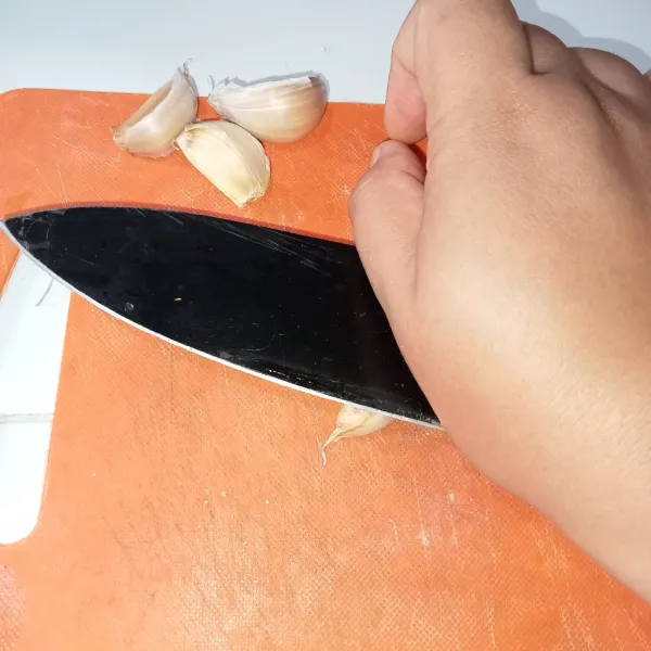 Geprek perlahan bawang dengan meletakkan di bawah pisau.