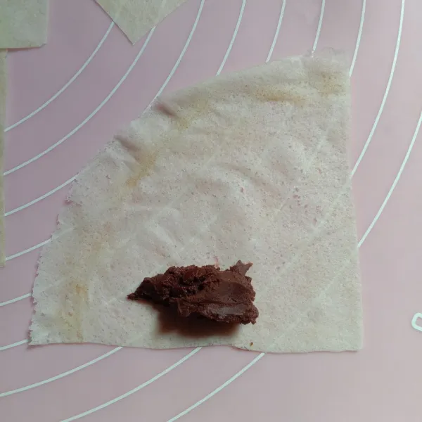 Potong kulit lumpia jadi empat bagian. Isi satu lembar bagiannya dengan secukupnya selai cokelat.