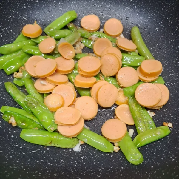 Masukkan irisan sosis. Aduk rata dengan tumisan.