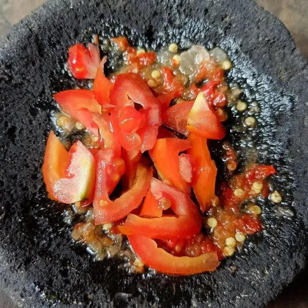 Masukkan irisan tomat dan ulek lagi sampai tomat hancur.