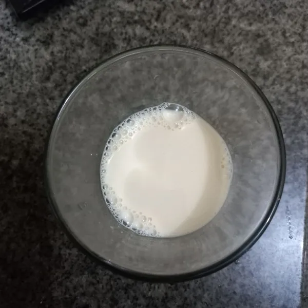 Tuang susu cair pada gelas.
