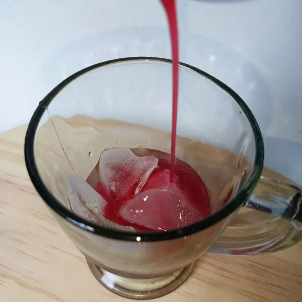 Masukkan es batu dan sirup cocopandan ke dalam gelas.