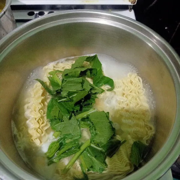 Siapkan panci lalu rebus air sampai mendidih lalu masukkan mie dan potongan daun sosin.