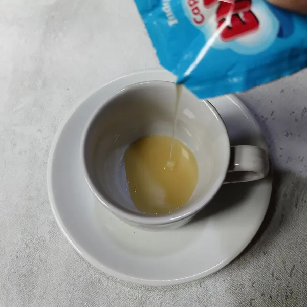 Masukkan krimer kental manis ke dalam cangkir atau gelas.
