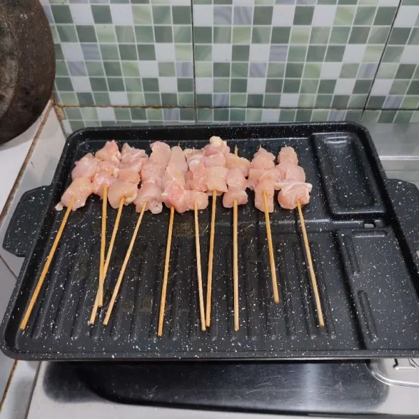 Panggang sate setengan matang di atas grill pan, panggang hingga daging ayam berubah warna saja.