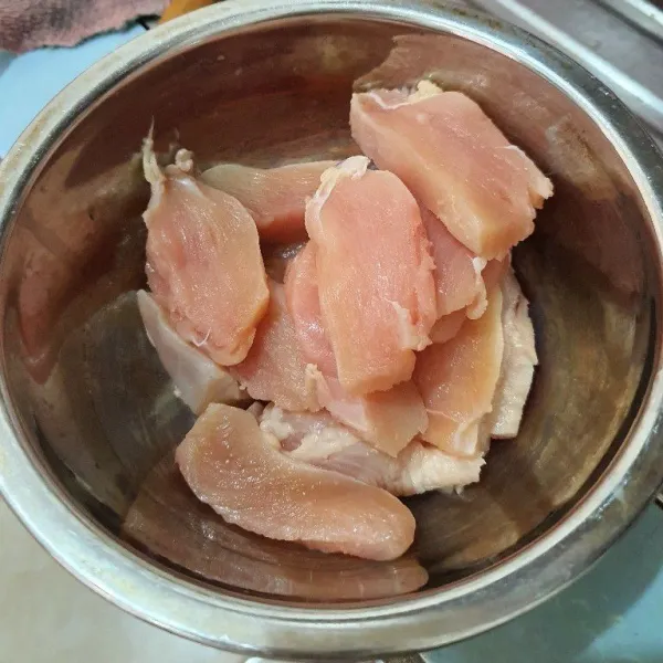 Potong-potong daging ayam ukuran kecil. Taruh potongan ayam dalam wadah.