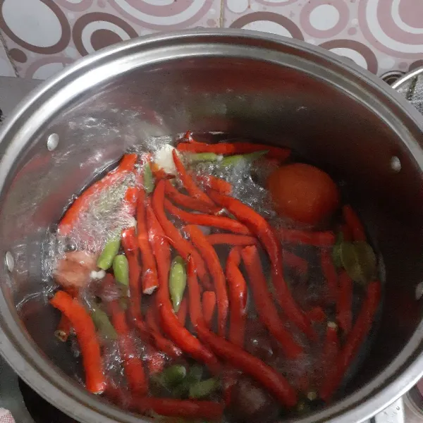 Didihkan air rebus cabe, tomat, bawang merah, dan bawang putih hingga empuk.