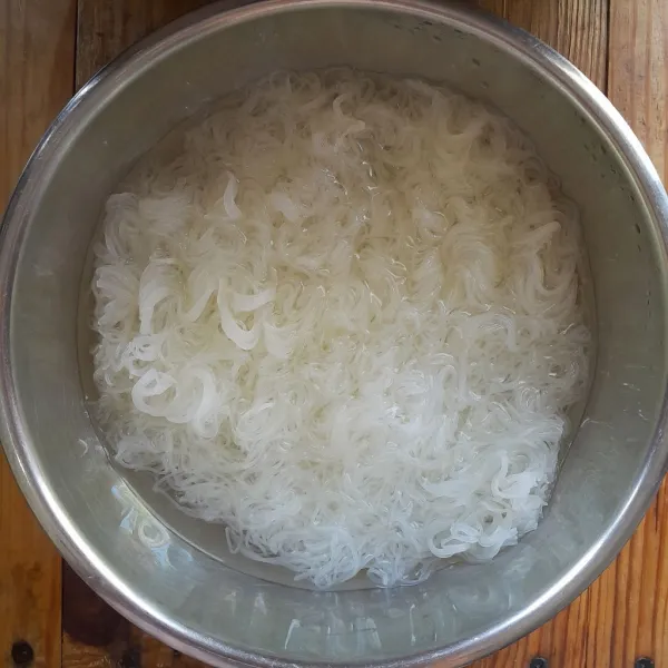 Siapkan wadah, masukkan bihun, tambahkan air panas. Biarkan hingga bihun lunak dan lembut, tiriskan. Saat bihun masih panas, tambahkan minyak wijen, kecap asin, kecap ikan, merica bubuk dan garam. Aduk rata.