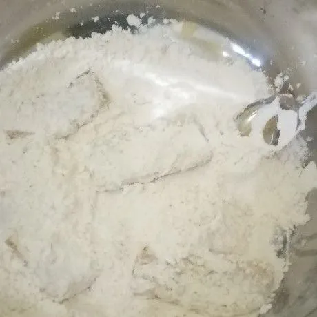 Gulingkan tempe ke dalam adonan kering sambil aduk hingga tempe terbalut tepung