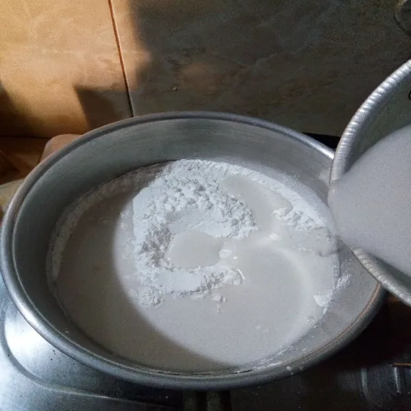Lalu tambahkan santan. Aduk hingga tepung beras larut bersama santan. Kemudian nyalakan api kecil.