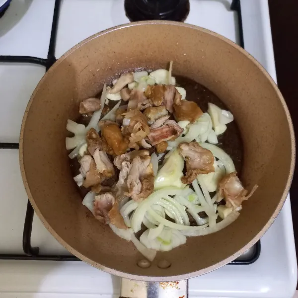 Tumis irisan bawang putih dan bawang bombay hingga harum, masukkan potongan daging paha ayam, aduk rata.