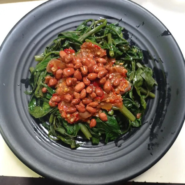 Tata kangkung pada piring, tarus sambal diatas kangkung lalu taburi kacang goreng, sajikan.