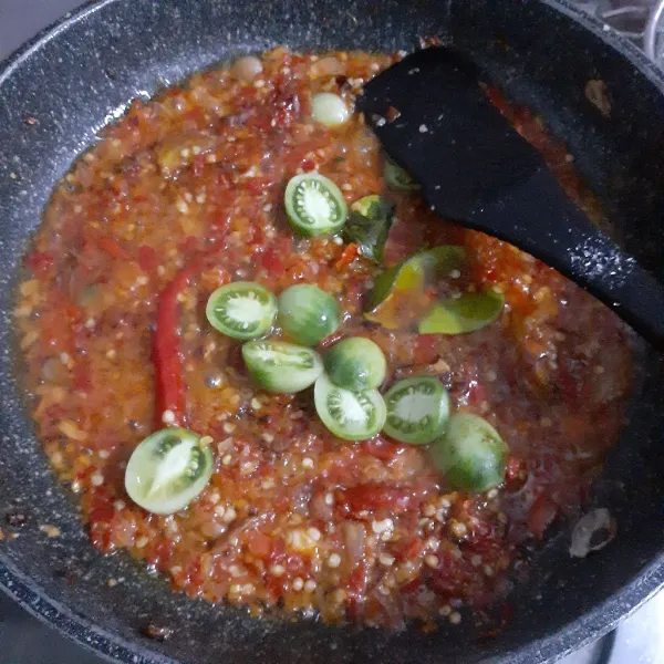 Masukkan tomat hijau, masak sesaat, matikan kompor. Tata ikan kembung bakar pada piring saji dan siram dengan sambal rica. Sajikan.