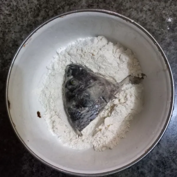 Gulingkan ikan pada sisa tepung terigu, pastikan tepung menempel pada ikan.