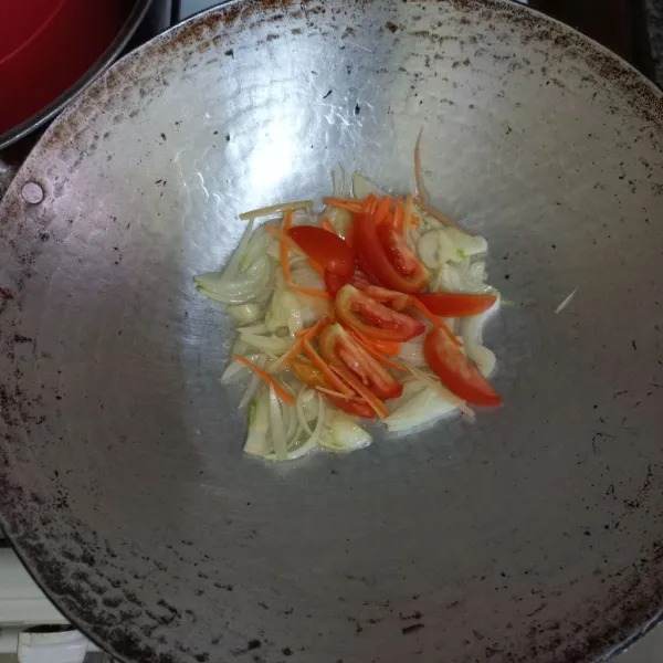 Tumis irisan bawang putih dan bawang bombay dengan minyak secukupnya hingga harum, lalu masukkan irisan tomat dan irisan korek wortel, aduk rata.