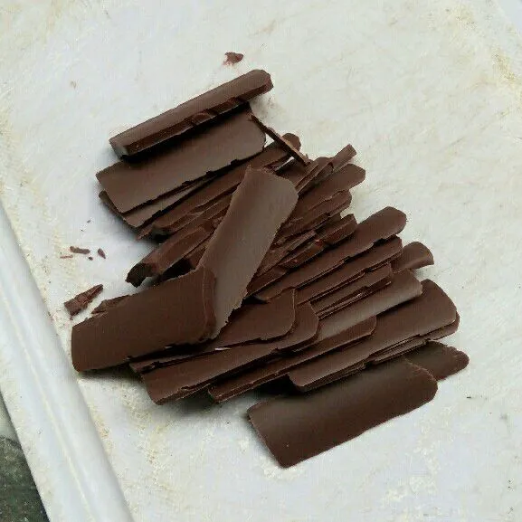 Potong coklat menjadi tipis agar memudahkan proses pelelehan.