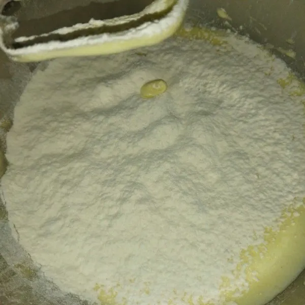 Lalu masukkan tepung terigu sambil diayak, mixer dengan kecepatan rendah hingga tercampur.