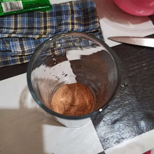 Tuang bubuk cokelat ke dalam gelas.