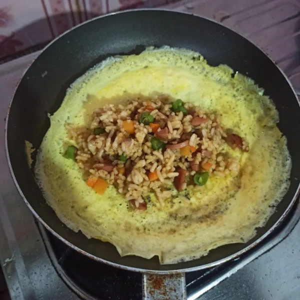 Matikan api taruh nasi goreng diatas omelette kemudian lipat kedua sisinya dan siap disajikan!