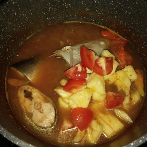 Koreksi rasa. Setelah ikan cukup matang, masukkan nanas dan tomat. Masak sebentar. Cek rasa kembali kemudian matikan api.