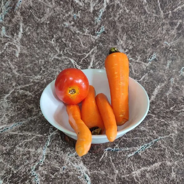 Cuci bersih tomat dan wortel, kemudian kupas kulit wortelnya.