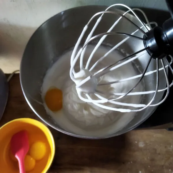 Kecilkan mixer dengan kecepatan sedang, masukkan kuning telur satu persatu hingga tercampur.