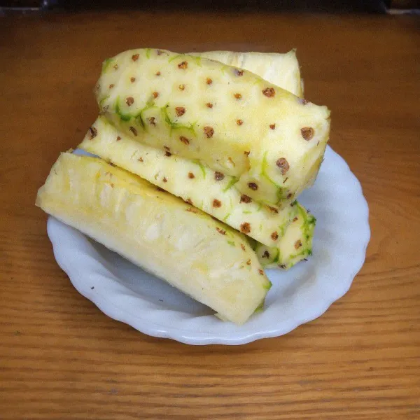 Kupas nanas tetapi mata nanasnya jangan dikupas. Lalu cuci bersih.