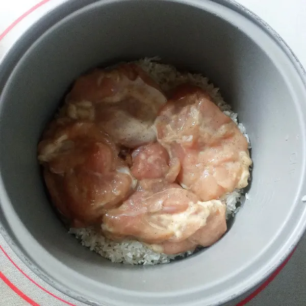 Aduk air dengan kaldu bubuk sampai larut. Tuang di atas beras kemudian tata potongan ayam beserta marinasinya.