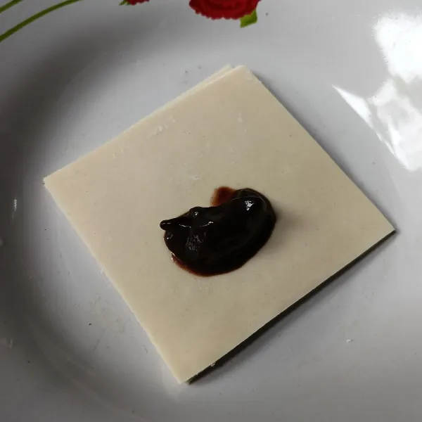 Letakkan satu sendok teh selai cokelat di atas kulit pangsit.