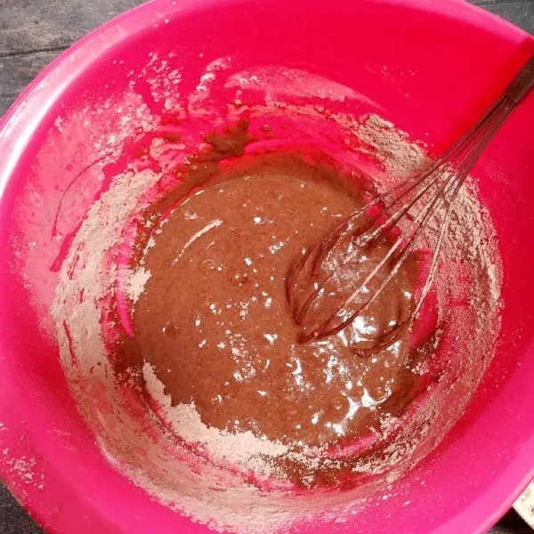 Masukkan sedikit demi sedikit adonan tepung, lalu masukkan lelehan dark cooking chocolate. Aduk rata, lakukan hingga adonan habis.