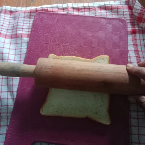 Gilas roti tawar dengan rolling pin hingga tipis.