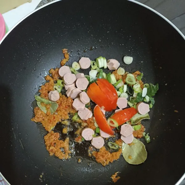 Masukkan potongan sosis, tomat, dan daun bawang. Tumis sebentar.