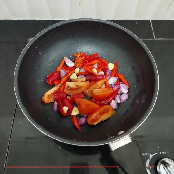 Dengan minyak bekas menggoreng ikan teri, lalu goreng cabai merah besar, cabai rawit, bawang merah, bawang putih dan tomat hingga layu. Angkat.