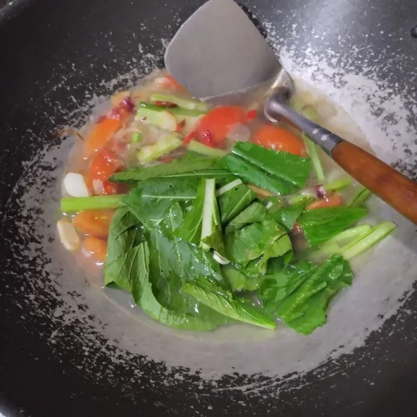 Tuang air, biarkan mendidih lalu masukkan tomat dan sawi. Masak hingga layu.