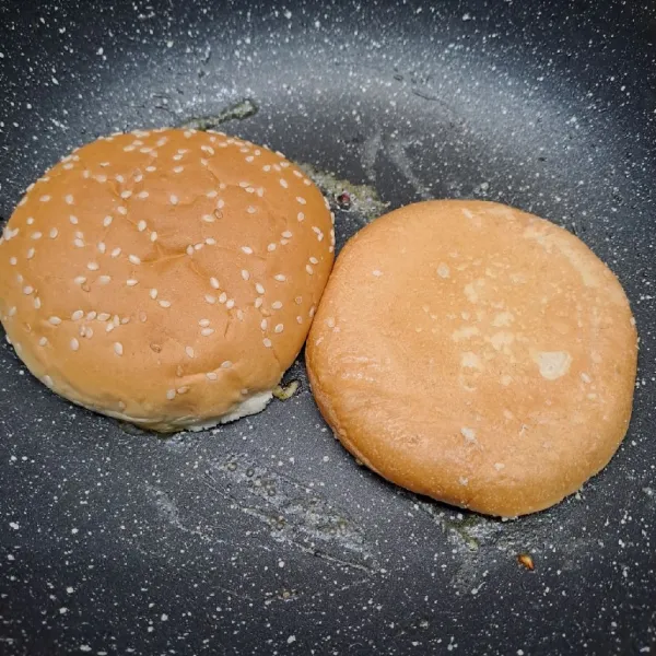 Oles roti burger dengan margarin. Panggang roti sampai sedikit kecokelatan.