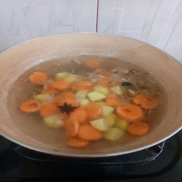 Masukkan air masak hingga mendidih, lalu masukkan kentang dan wortel masak hingga setengah matang.