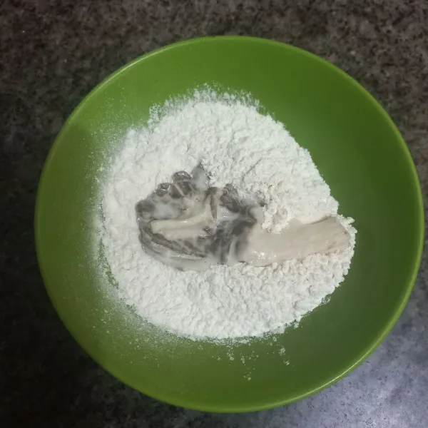 Gulingkan jamur pada tepung terigu, ratakan.