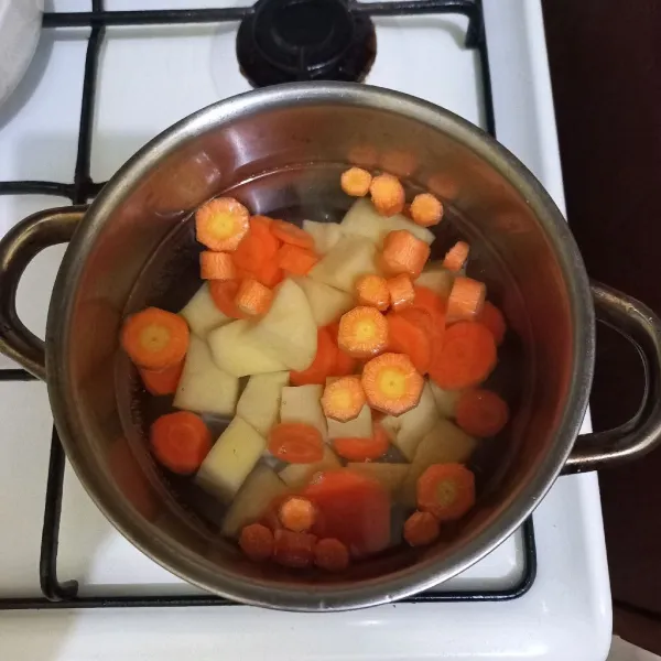 Rebus air dalam panci, masukkan irisan kentang dan wortel.