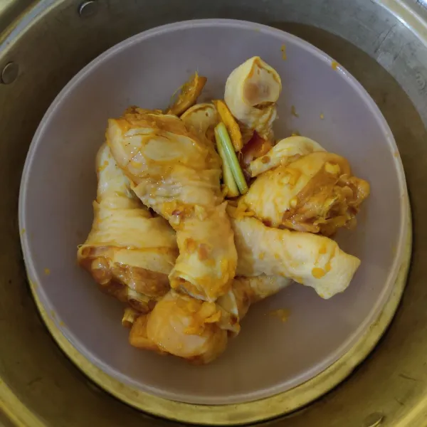 Panaskan kukusan, kukus ayam selama 25-30 menit. Matikan api, pisahkan ayam dan airnya.