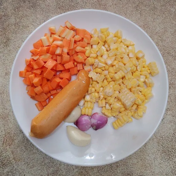 Potong dadu kecil wortel, serut jagung, belah menjadi dua sosis, cincang halus bawang merah dan bawang putih.