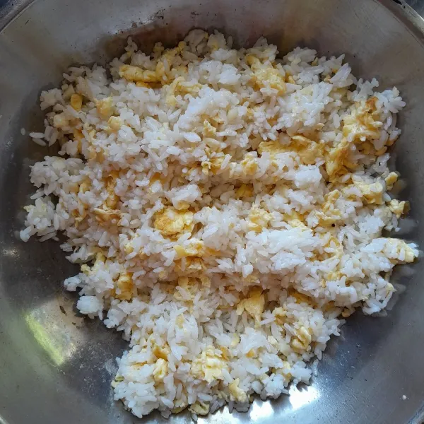 Kemudian masukkan nasi putih, besarkan api kompor. Aduk nasi, telur dan bawang putih hingga tercampur rata. Kecilkan api kompor.