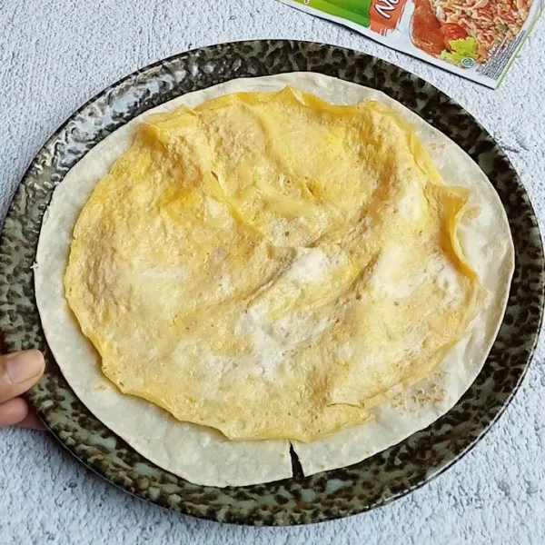 Siapkan kulit tortilla dan beri telur dadar diatasnya .