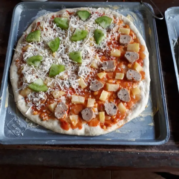 Olesi dough dengan saos dan ratakan. Tata kentang dan bakso di atas saos. Taburi keju mozzarella dan terakhir isi dengan tomat hijau.