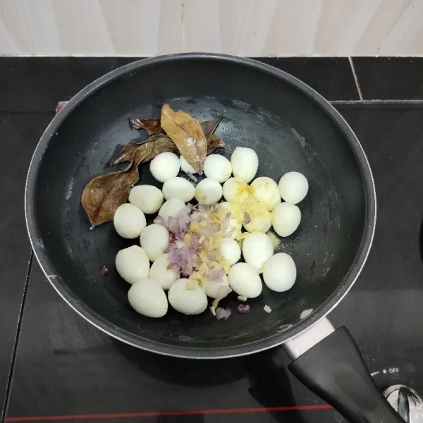 Masukkan telur puyuh ke dalam panci. Tambahkan bawang merah, bawang putih dan daun salam.
