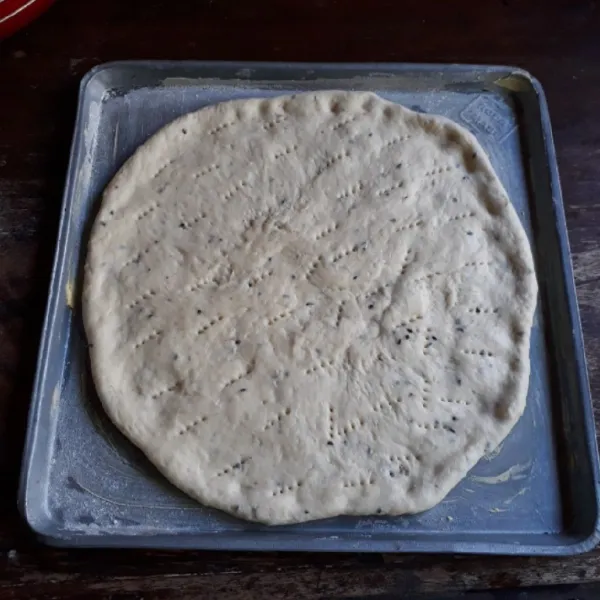 Kempiskan adonan dough. Pipihkan dan letakkan di atas loyang yang sudah dioles tipis margarin. Tusuk-tusuk dough dengan garpu.