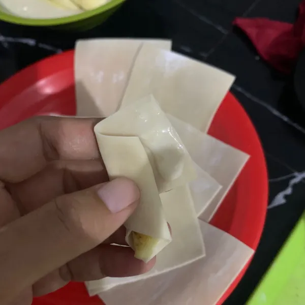 Gulung pisang di dalam kulit pangsit dan ujungnya di beri larutan tepung terigu