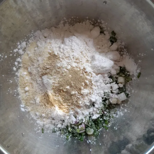 Siapkan wadah, masukkan irisan daun bawang, tepung tapioka, bawang putih bubuk, garam, merica bubuk dan kaldu bubuk. Aduk rata.