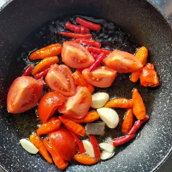 Panaskan secukupnya minyak goreng, masukkan bawang putih, terasi, potongan cabai rawit, cabai merah keriting dan tomat. Masak hingga semua layu, angkat.
