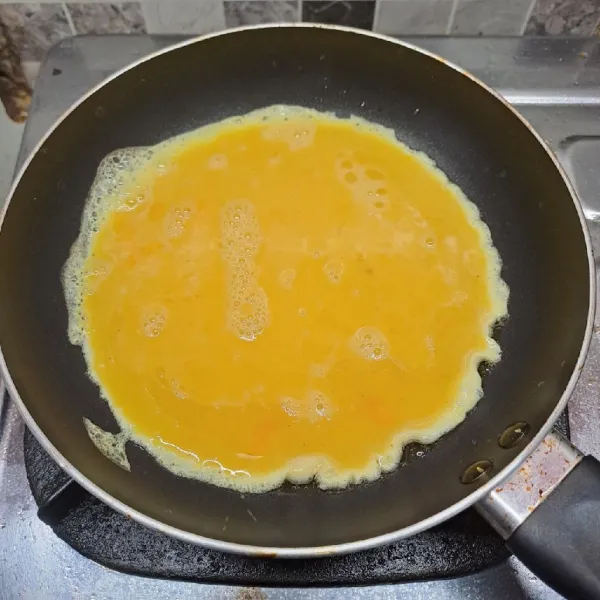 Panaskan teflon dengan sedikit minyak goreng. Tuang adonan telur secara merata, masak dengan api kecil.