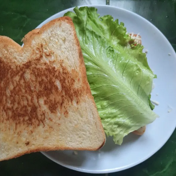 Tutup dengan daun selada dan terakhir susun roti di atasnya.